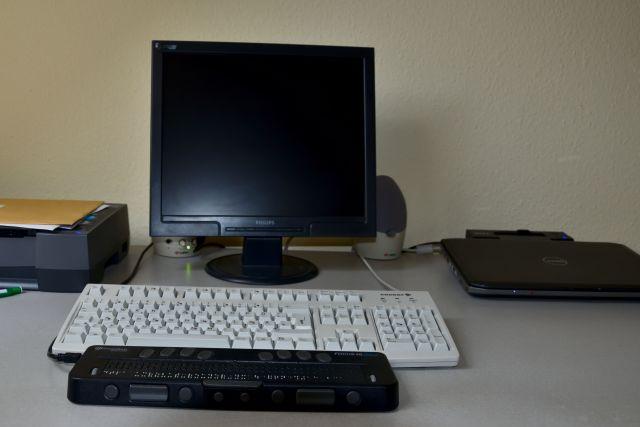 Foto: Arbeitsplatz mit Braillezeile, Tastatur, schwarzem Bildschirm und ohne Maus.
